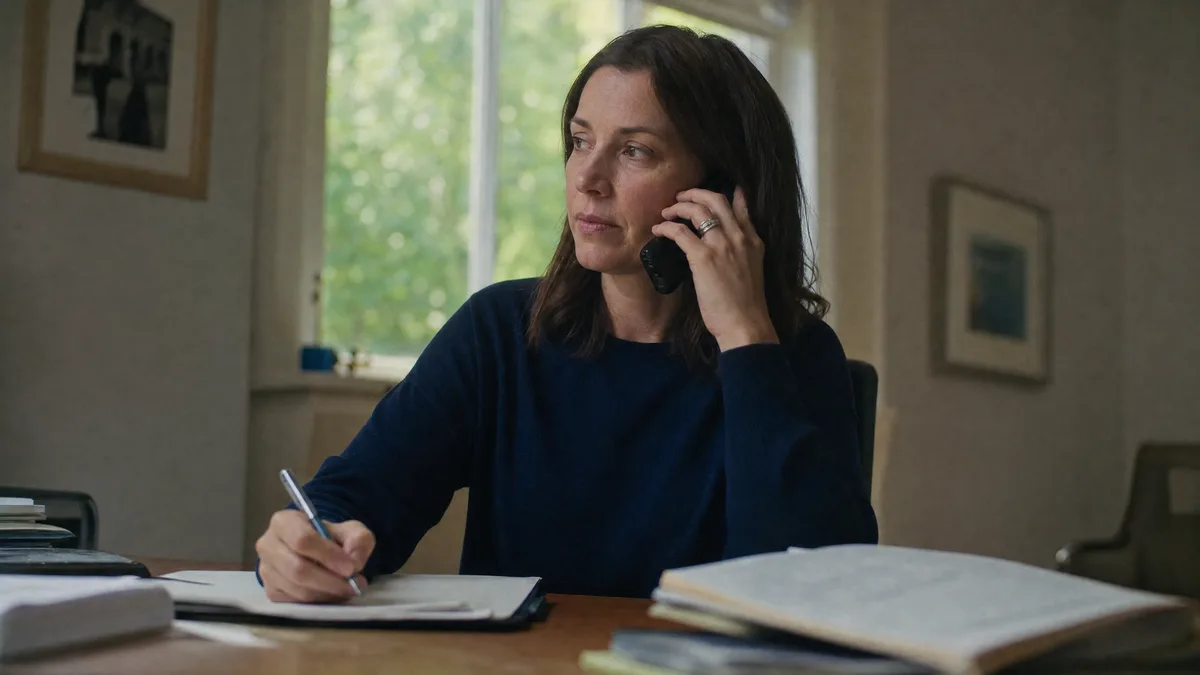 A pediatrician at a desk on the phone, notes and an open folder in front of them.